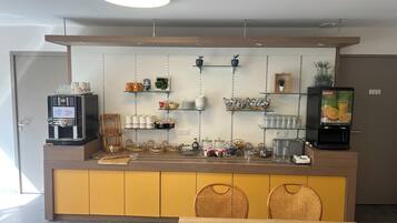 Eine moderne Küche mit Kaffeemaschine, Regalen voller Küchenutensilien und einem Fernseher, der eine Werbung zeigt.