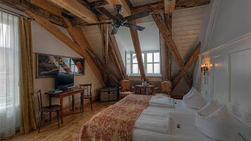 A bedroom with a wooden ceiling, a bed, a television, and a desk with chairs.