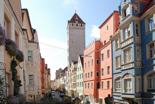 Una calle estrecha flanqueada por edificios coloridos, una torre destacada y un letrero que dice 'Zinn Haus'.