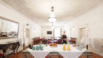 Ein Esszimmer mit einem langen Tisch, der für eine Mahlzeit gedeckt ist, umgeben von Stühlen, und einer von der Decke hängenden Kristallleuchter.
