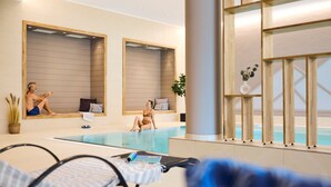 A modern indoor swimming pool area with lounge chairs, a large mirror, and a view of the sea. - ROBINSON FIEBERBRUNN - Adults only (Fieberbrunn)