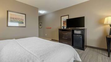 A hotel room with a large bed, a flat-screen TV, a microwave, and a small cabinet.