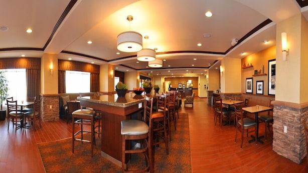 A hotel lobby with a bar area, multiple seating options, and a reception desk.