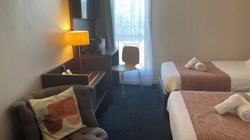 Een hotelkamer met twee bedden, een bureau, een stoel en een televisie.