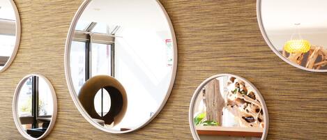 Un mur orné de plusieurs miroirs ronds qui reflètent différents éléments de l’intérieur.