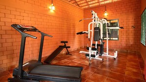 A gym with a treadmill, bench, and weight machine. - Coco Bay Resort (Kottayam)
