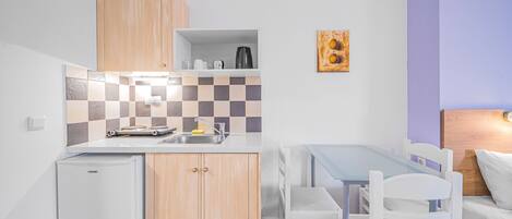 A compact kitchen with a refrigerator, a sink, and a dining area with a table and chairs.