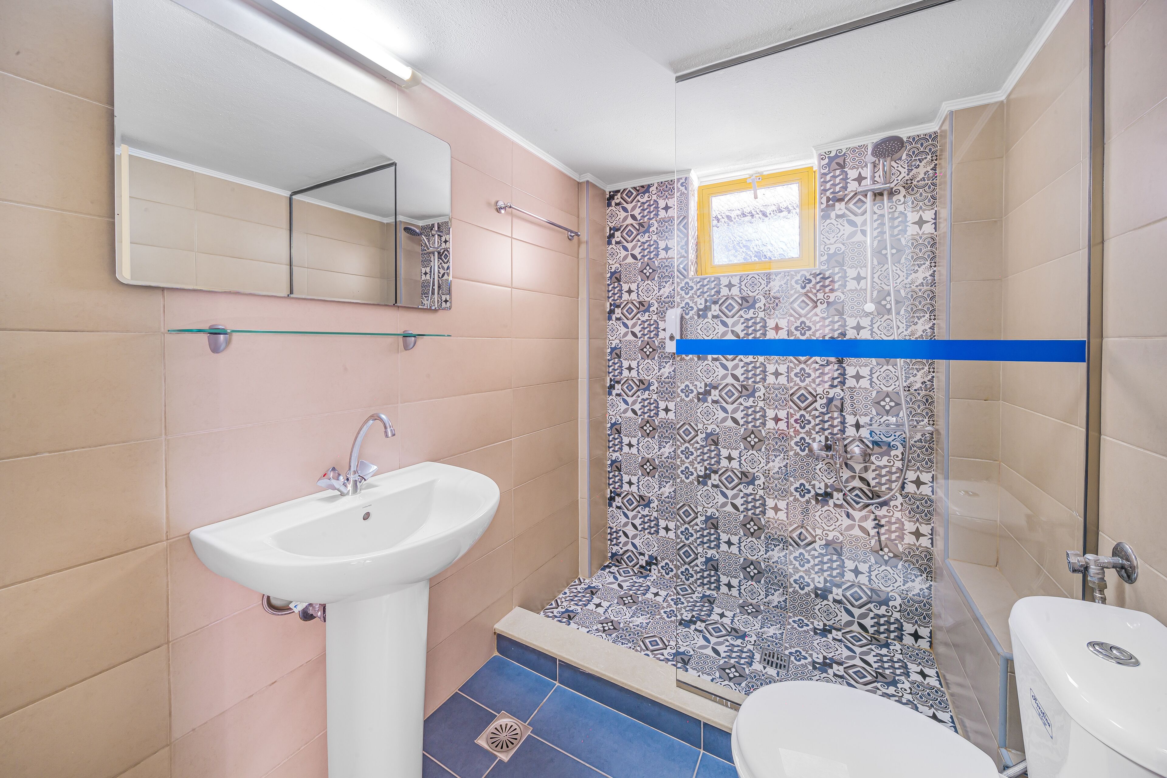 Un baño con lavamanos, inodoro y zona de ducha.