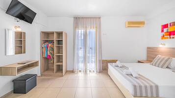 Een hotelkamer met een bed, een aan de muur bevestigde televisie, een kledingkast en een raam met gordijnen.