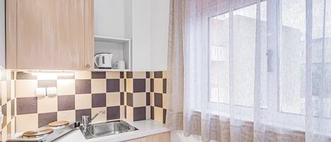 Una cocina compacta con lavavajillas, un lavabo y una cafetera sobre la encimera.