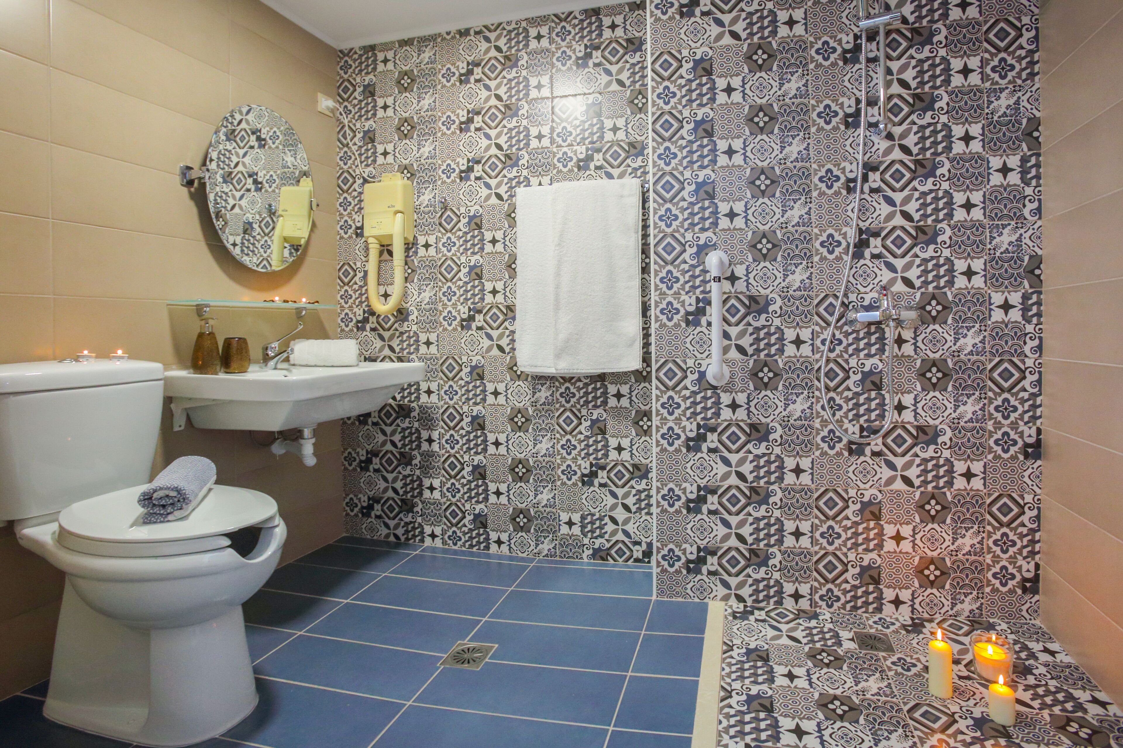 Une salle de bain avec des toilettes, un lavabo et des carreaux décorés.