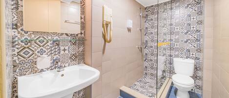 A bathroom with a sink, toilet, and shower.