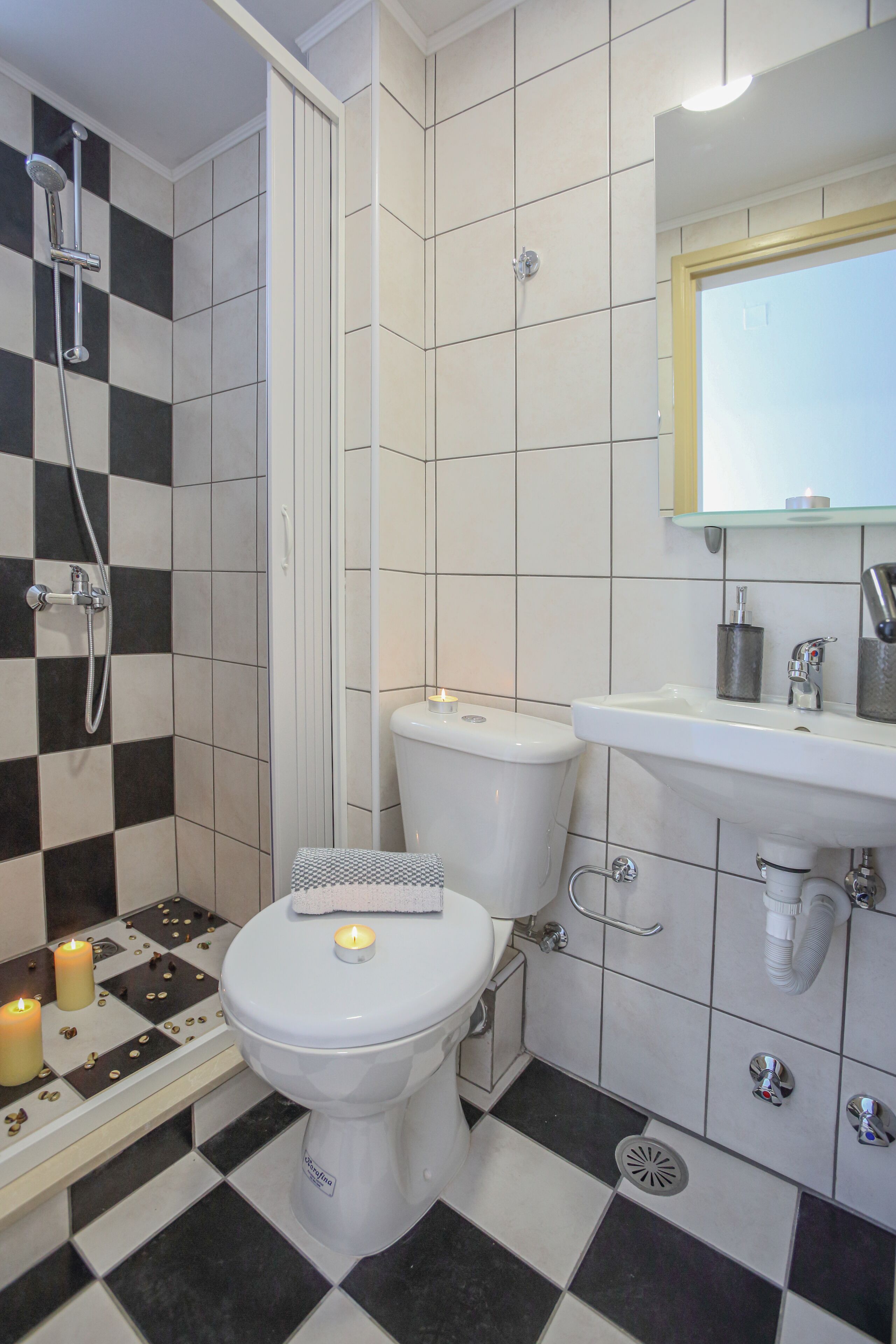 A bathroom with a black and white checkered floor, a toilet, a sink, and a shower.