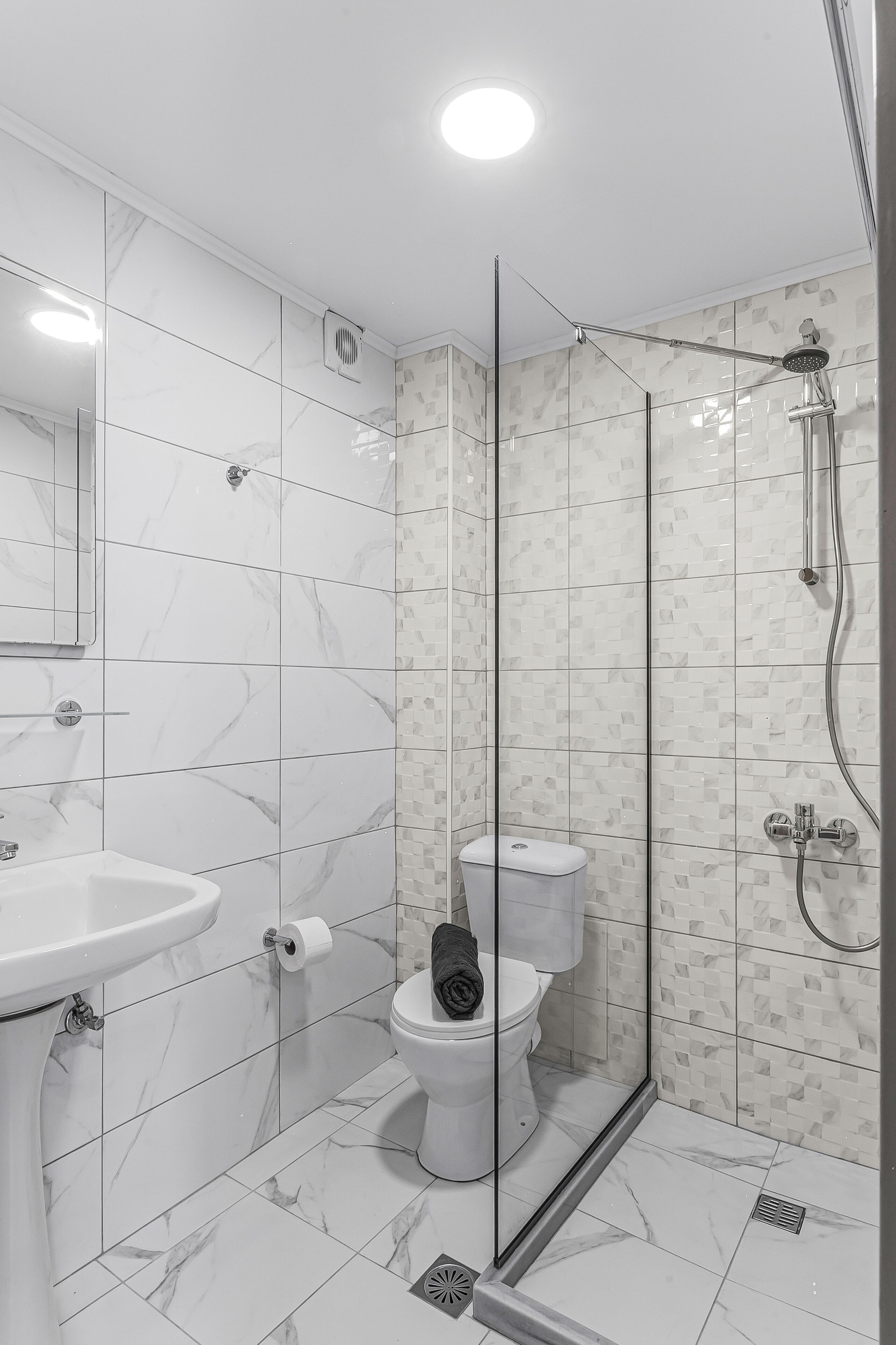 A modern bathroom with a glass-enclosed shower, a toilet, and a sink.
