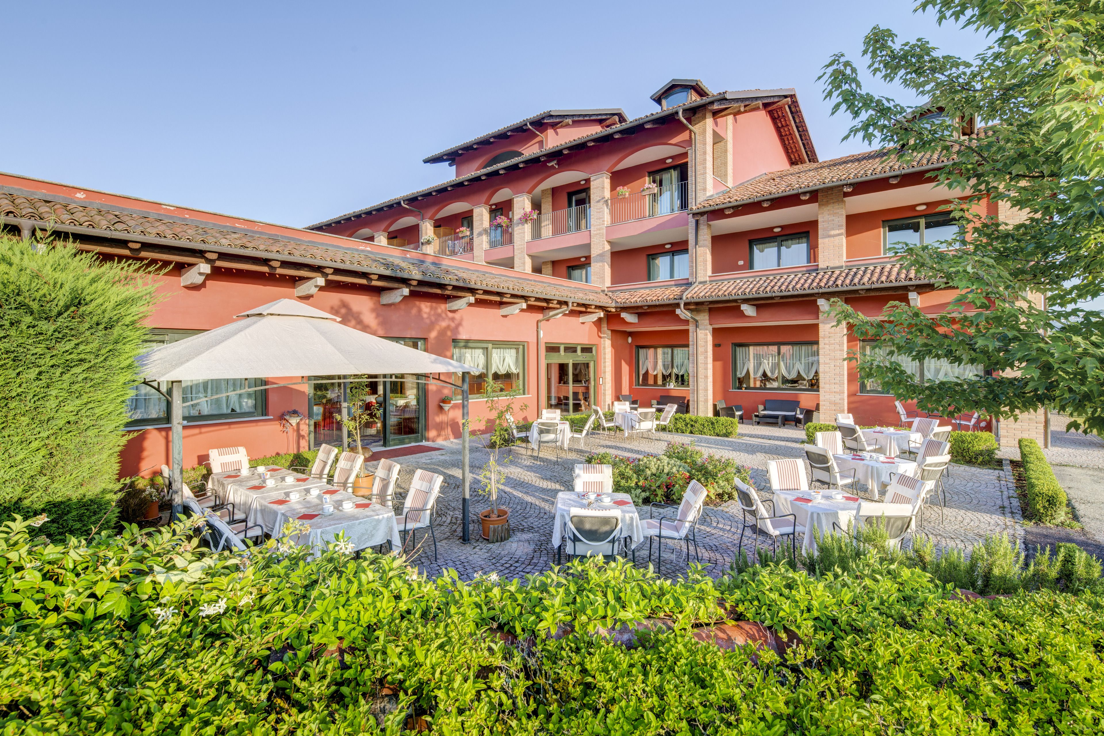 A hotel with outdoor seating, a covered patio, and a garden area.