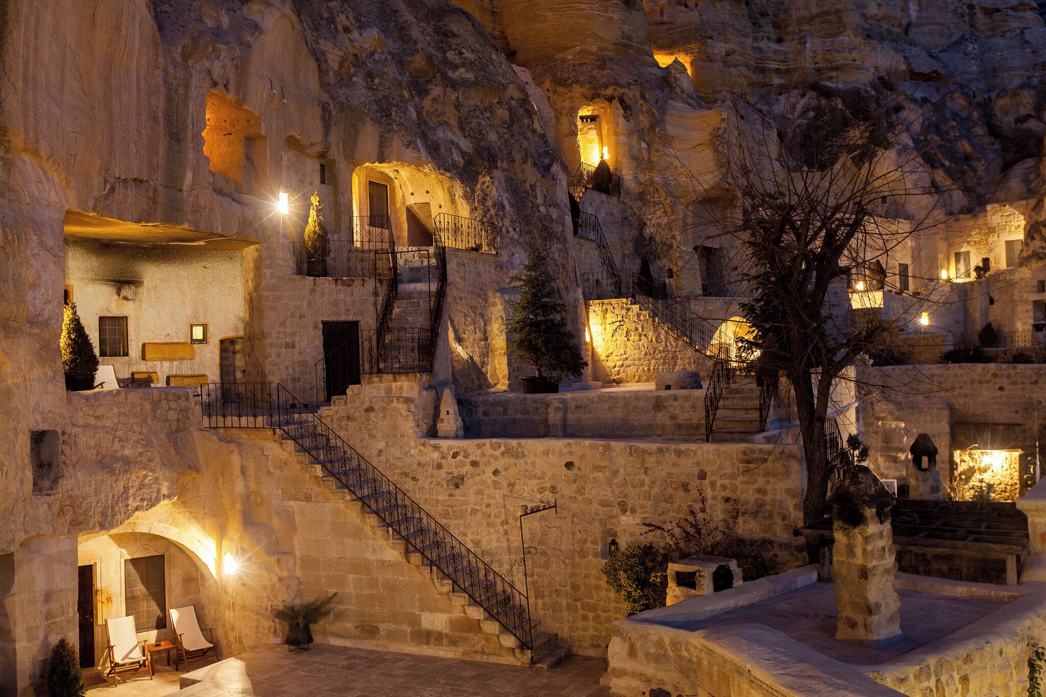 A historic stone building with multiple levels, staircases, and illuminated rooms.
