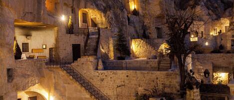 A historic stone building with multiple levels, staircases, and illuminated rooms.