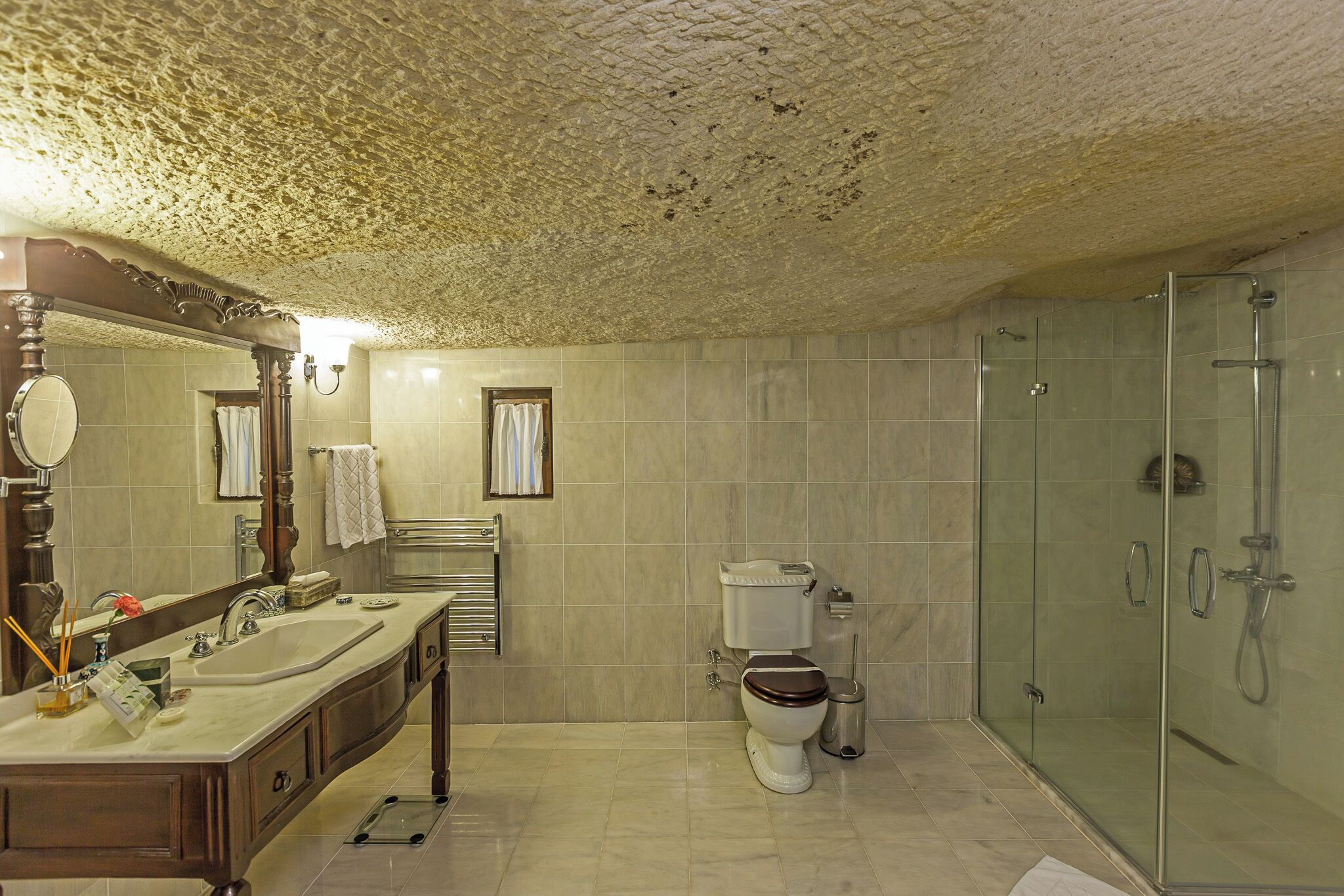 A bathroom with a double sink, a toilet, a shower, and a large mirror.