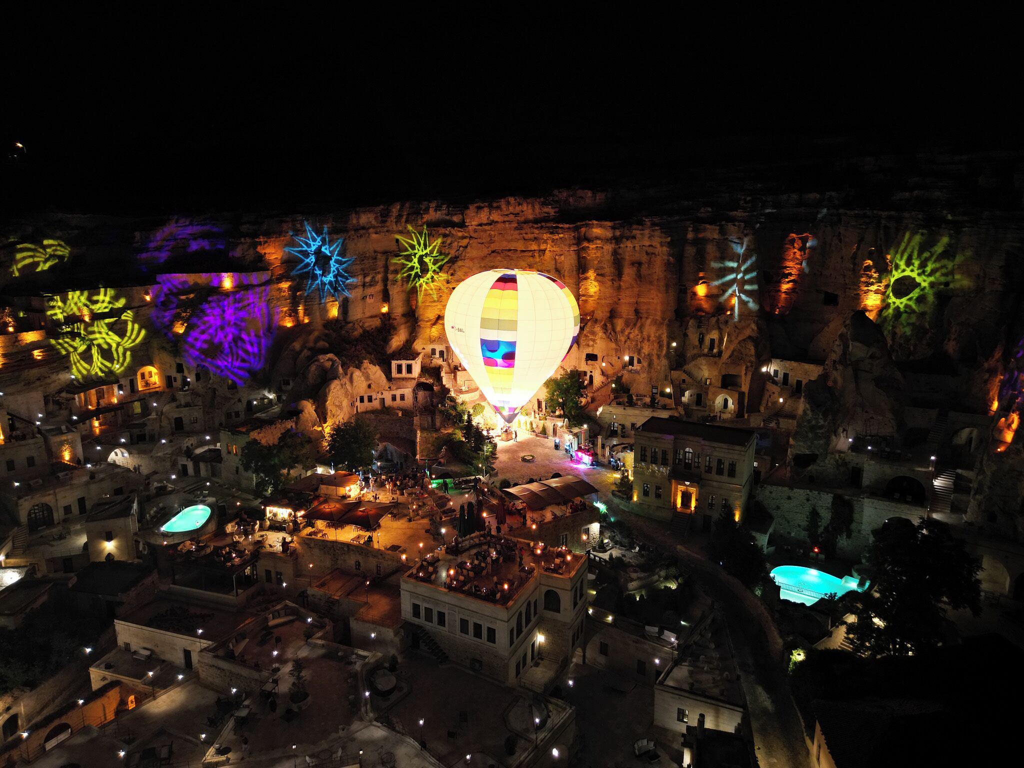 A model of a town with a large hot air balloon in the center, surrounded by buildings and illuminated by colorful lights.