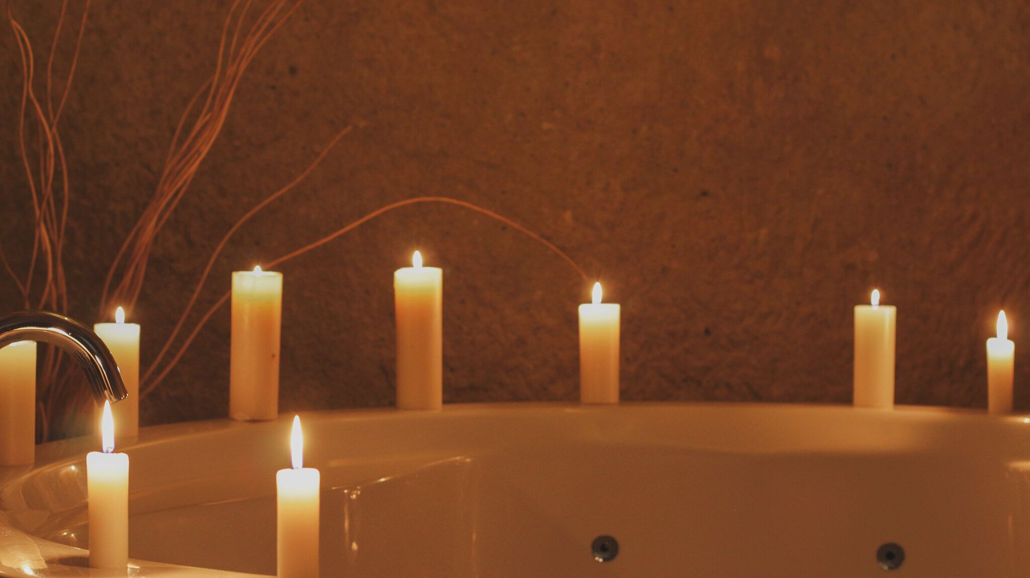 A bathtub with multiple lit candles around it.
