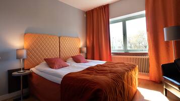 Une chambre d’hôtel moderne avec un grand lit, deux lampes de chevet, une vue sur l’extérieur par une fenêtre et un radiateur.
