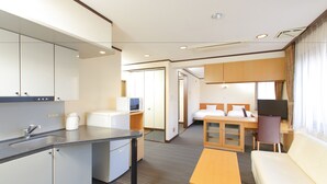 A hotel room with a kitchenette, a bed, a sofa, a TV, and a desk. - Flexstay Inn Sugamo (Tokyo)