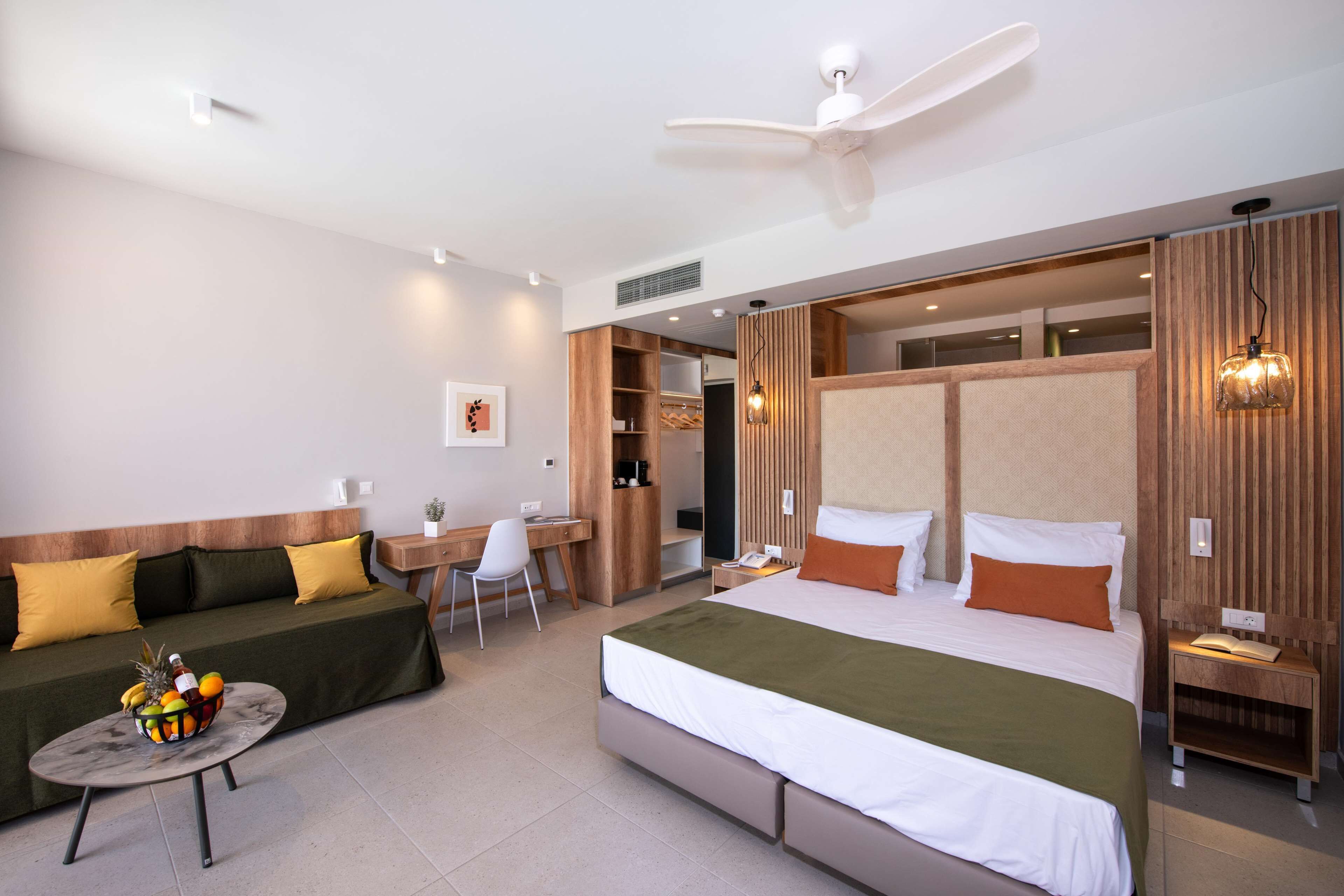 A hotel room with a bed, a sofa, a desk, and a chair.