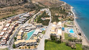 An aerial view of a coastal resort with multiple buildings, a swimming pool, and a beach. - Kiani Beach Resort Family (Chania)