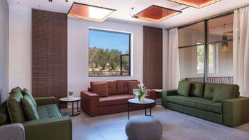 A modern living room with two sofas, a round ottoman, and a small table with a plant.