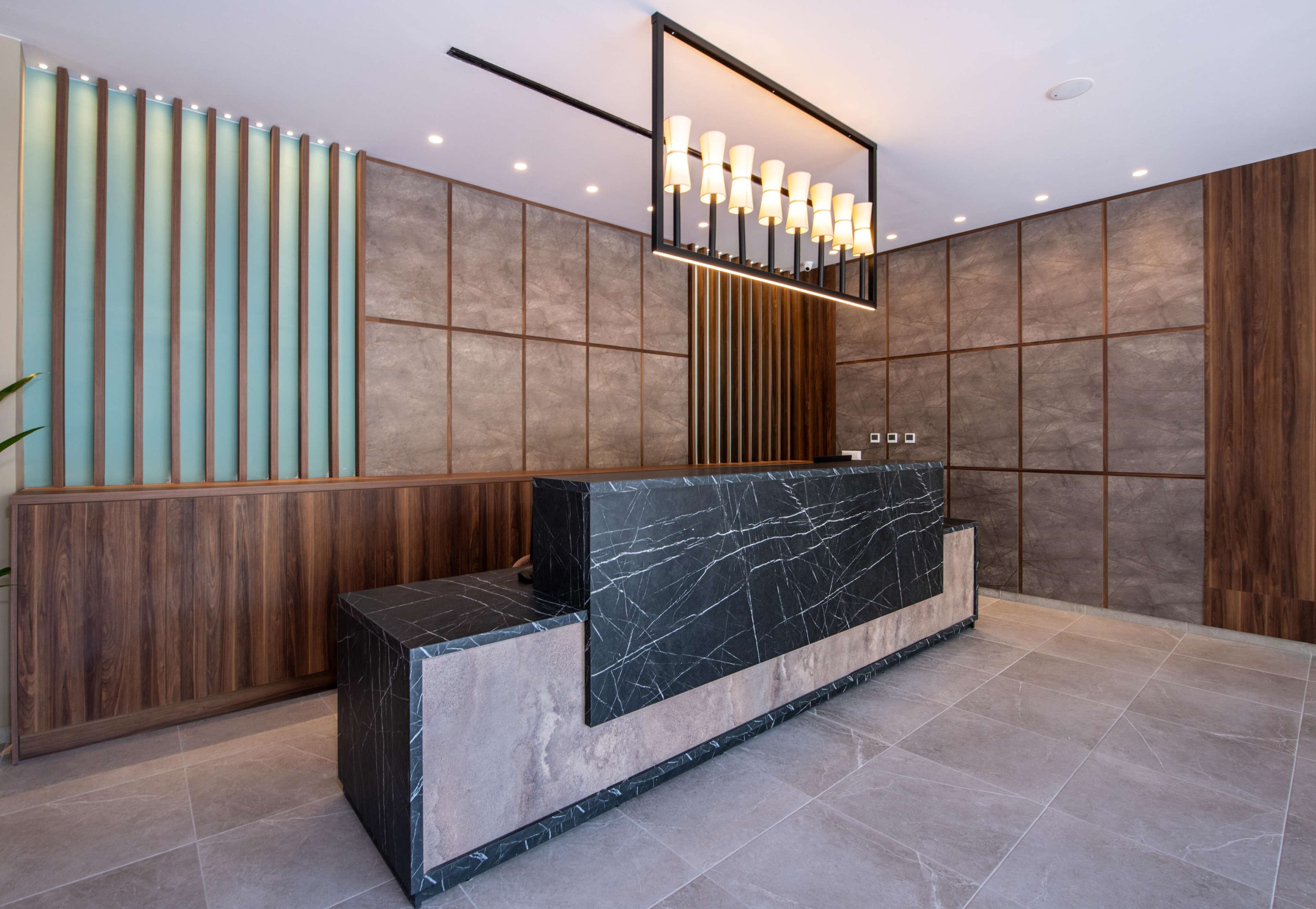 A reception area with a marble counter, wooden paneling, and a modern light fixture.