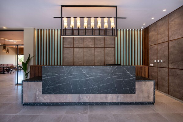 A reception desk with a marble top, flanked by vertical wooden slats and a large wall panel. - Kiani Beach Resort Family (Chania)
