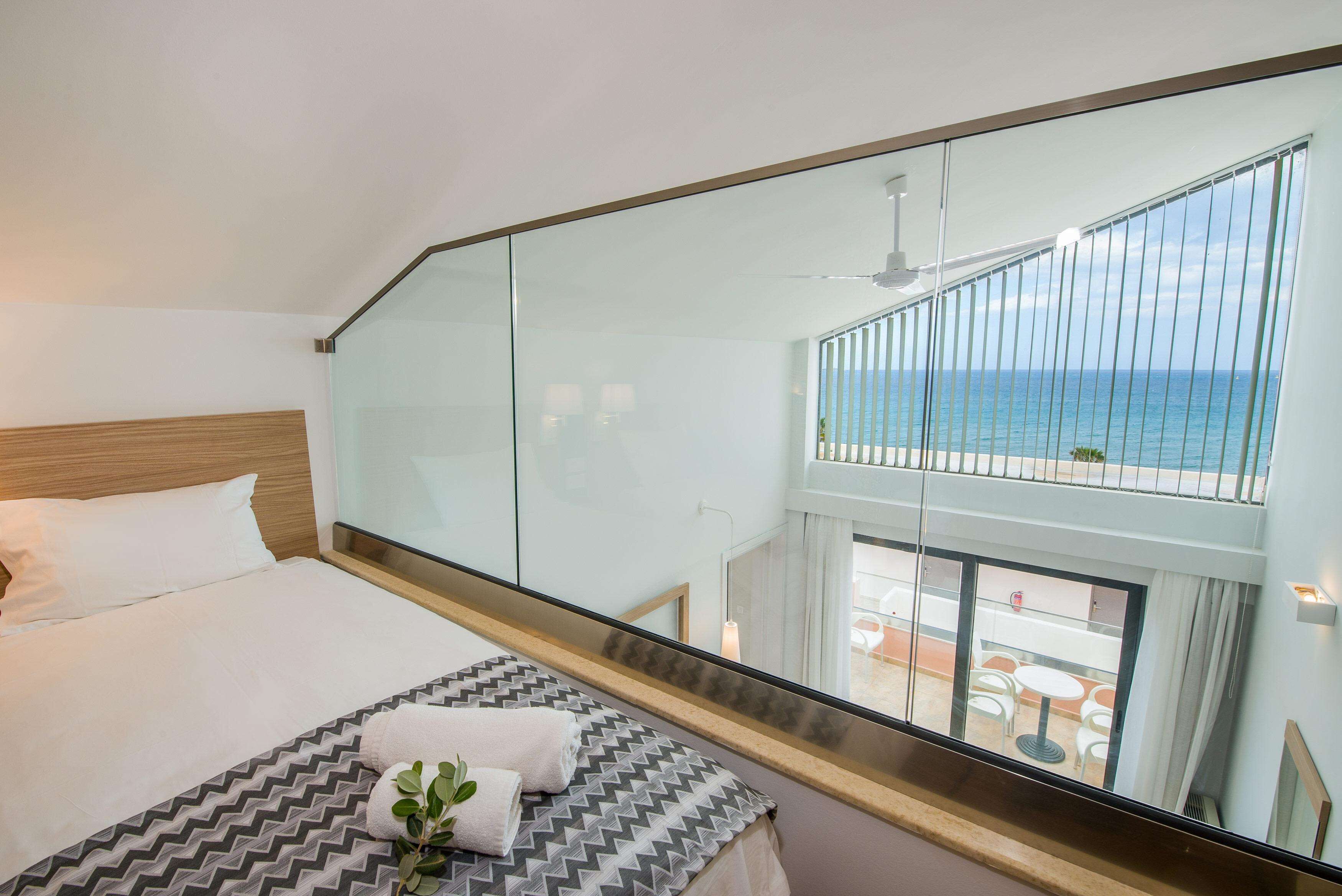 Ein Hotelzimmer mit großem Bett, Meerblick vom Balkon und modernem Interieur.
