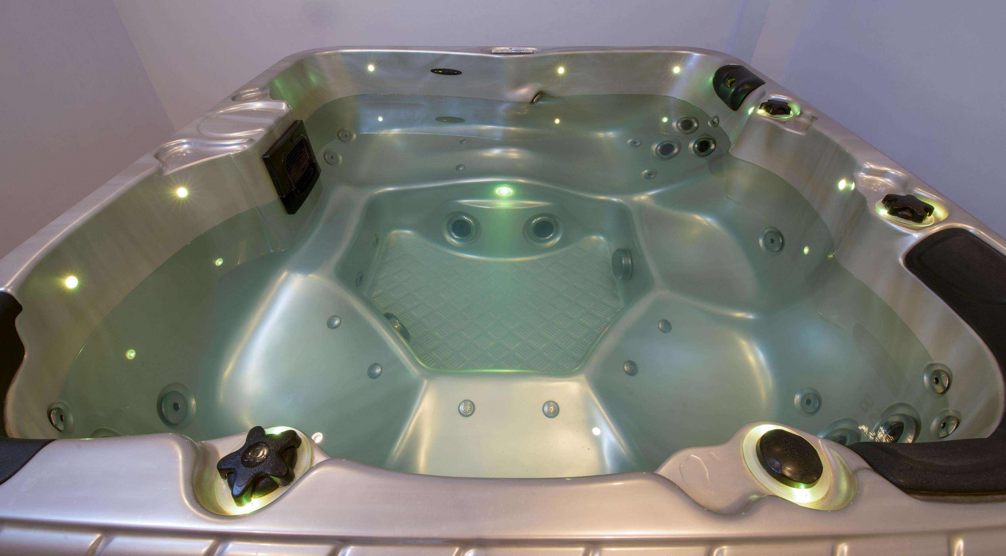 A hot tub with a hexagonal shape, multiple jets, and a control panel.