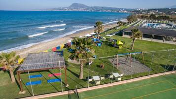 A beachside property with a fenced playground, a tennis court, and a pool area.