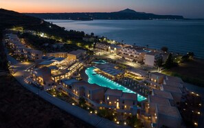 Un resort con piscina central, varias edificaciones y vista al mar.