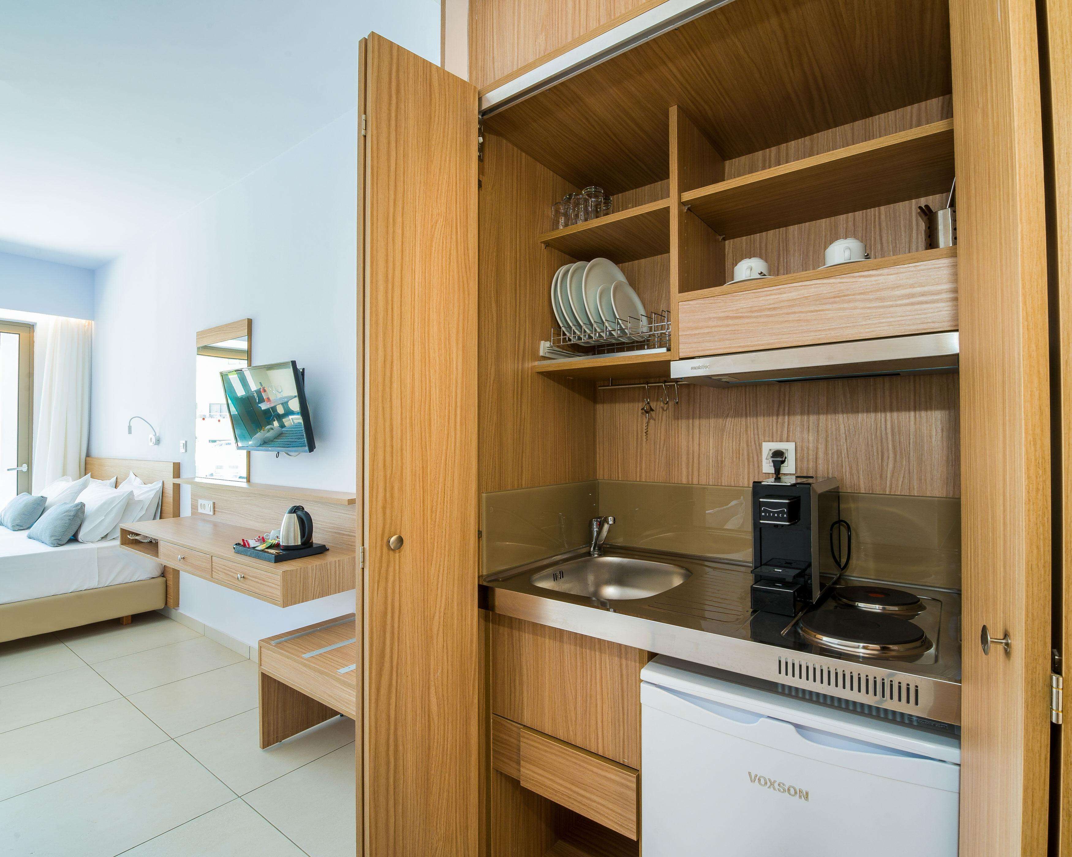 A compact kitchenette with a built-in stove, a sink, and a small refrigerator.