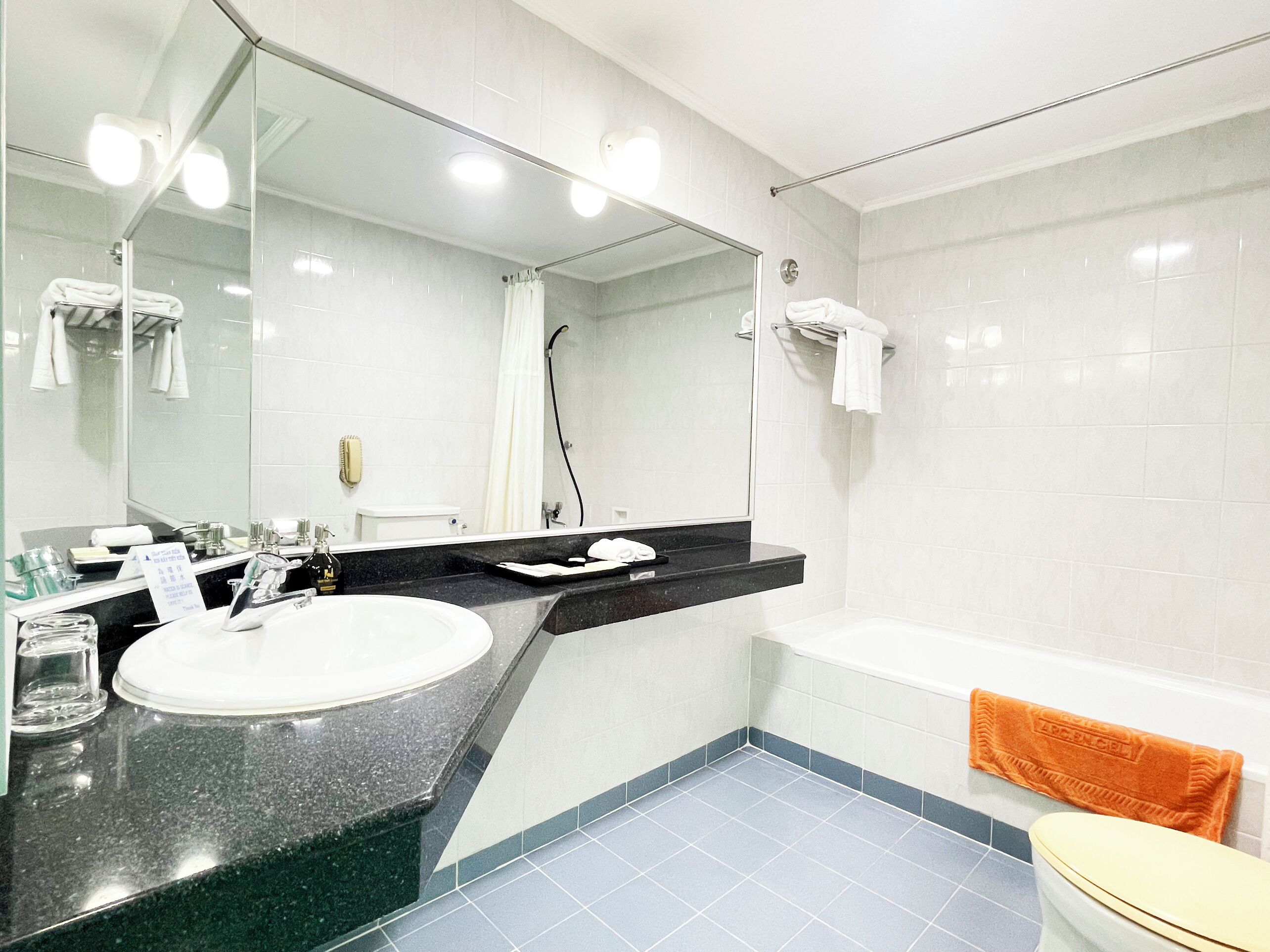 Une salle de bain moderne avec un grand miroir, un lavabo, une baignoire et des toilettes.