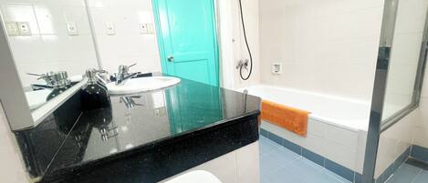 A modern bathroom with a black countertop, white sink, and a shower with a glass door.