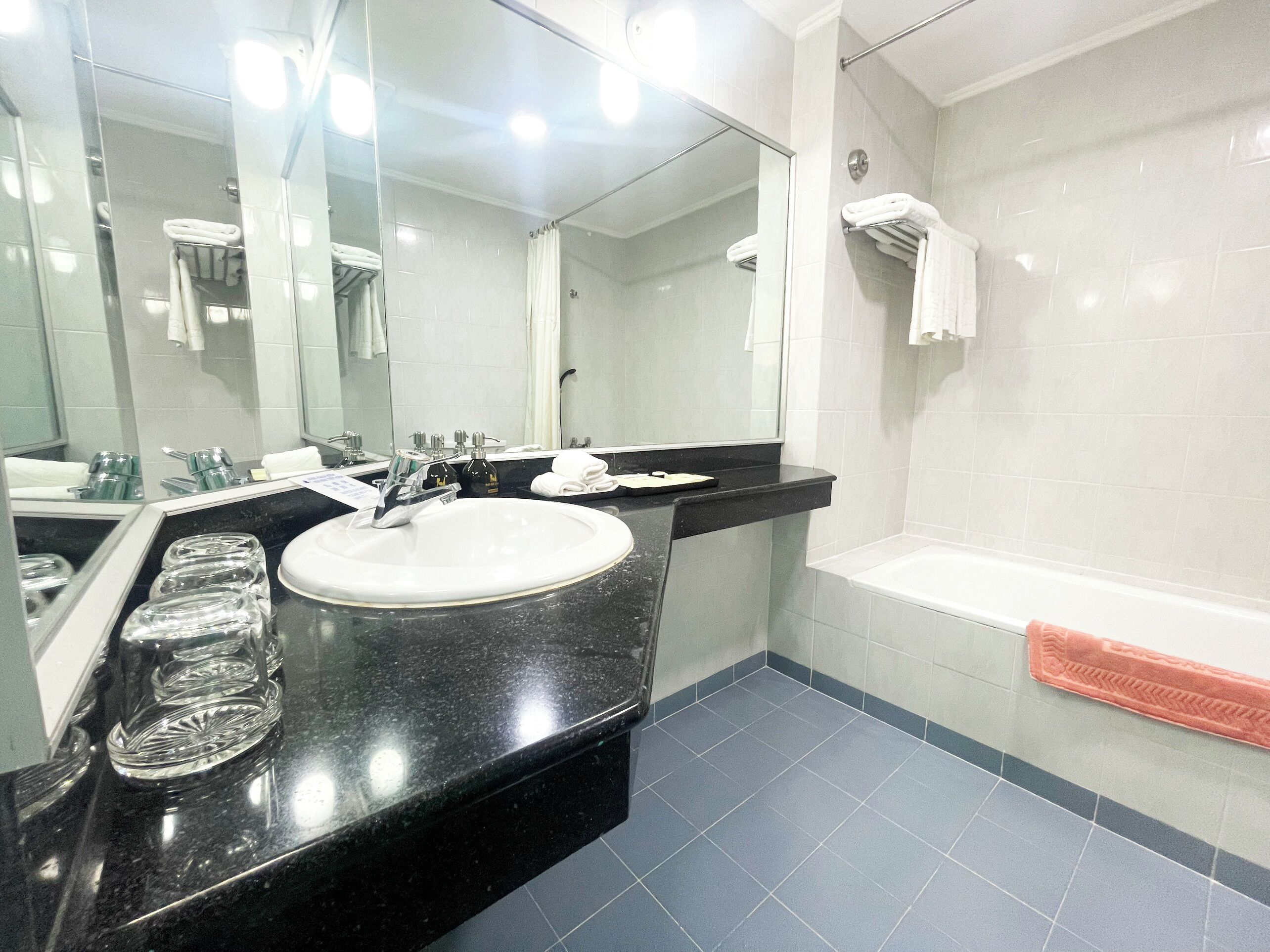 A modern bathroom with a black countertop, white sink, and a large mirror.