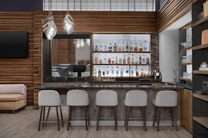 A modern bar area with a wooden bar counter, four bar stools, and a variety of liquor bottles displayed on shelves. - Hyatt Herald Square New York (New York)