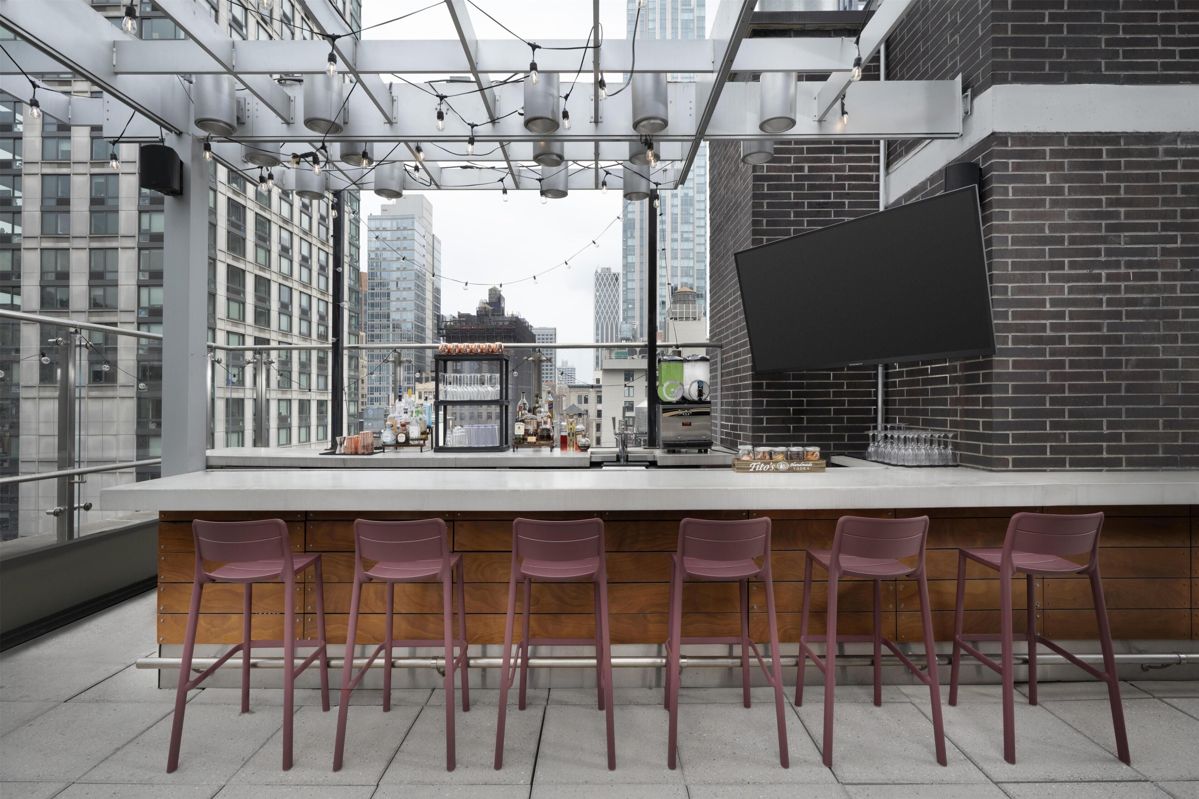 A bar area with a modern design, featuring a long counter with bar stools and a view of the cityscape.
