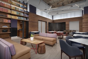 A modern library with bookshelves, seating areas, and tables. - Hyatt Herald Square New York (New York)