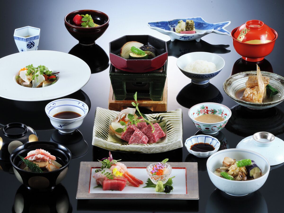 Verschiedene japanische Gerichte und traditionelles Servicewaren sind auf einem Tisch angerichtet.