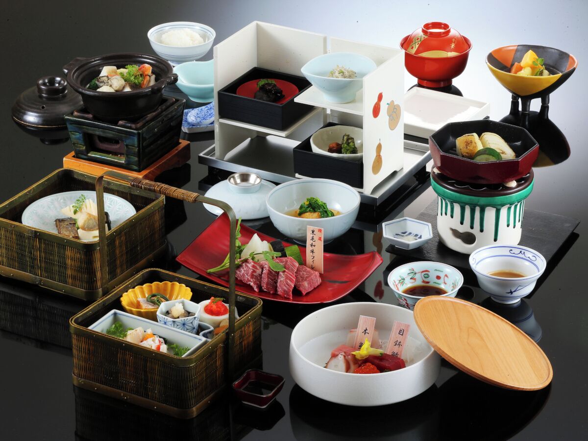 Diversos pratos e tigelas dispostos sobre uma mesa, incluindo um pote quente, sushi e acompanhamentos variados.