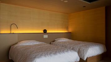 A hotel room with two beds, a wall-mounted light fixture, and a ceiling with recessed lighting.