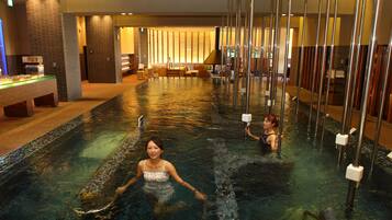 A pool area with a long, narrow pool, a reception desk, and seating areas.