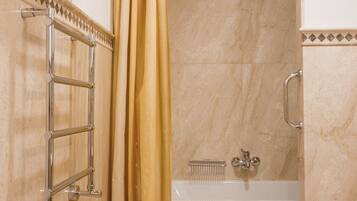 Un baño con bañera, cortina de ducha y toallero con toallas dobladas.