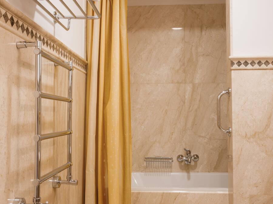 Un baño con bañera, cortina de ducha y toallero con toallas dobladas.