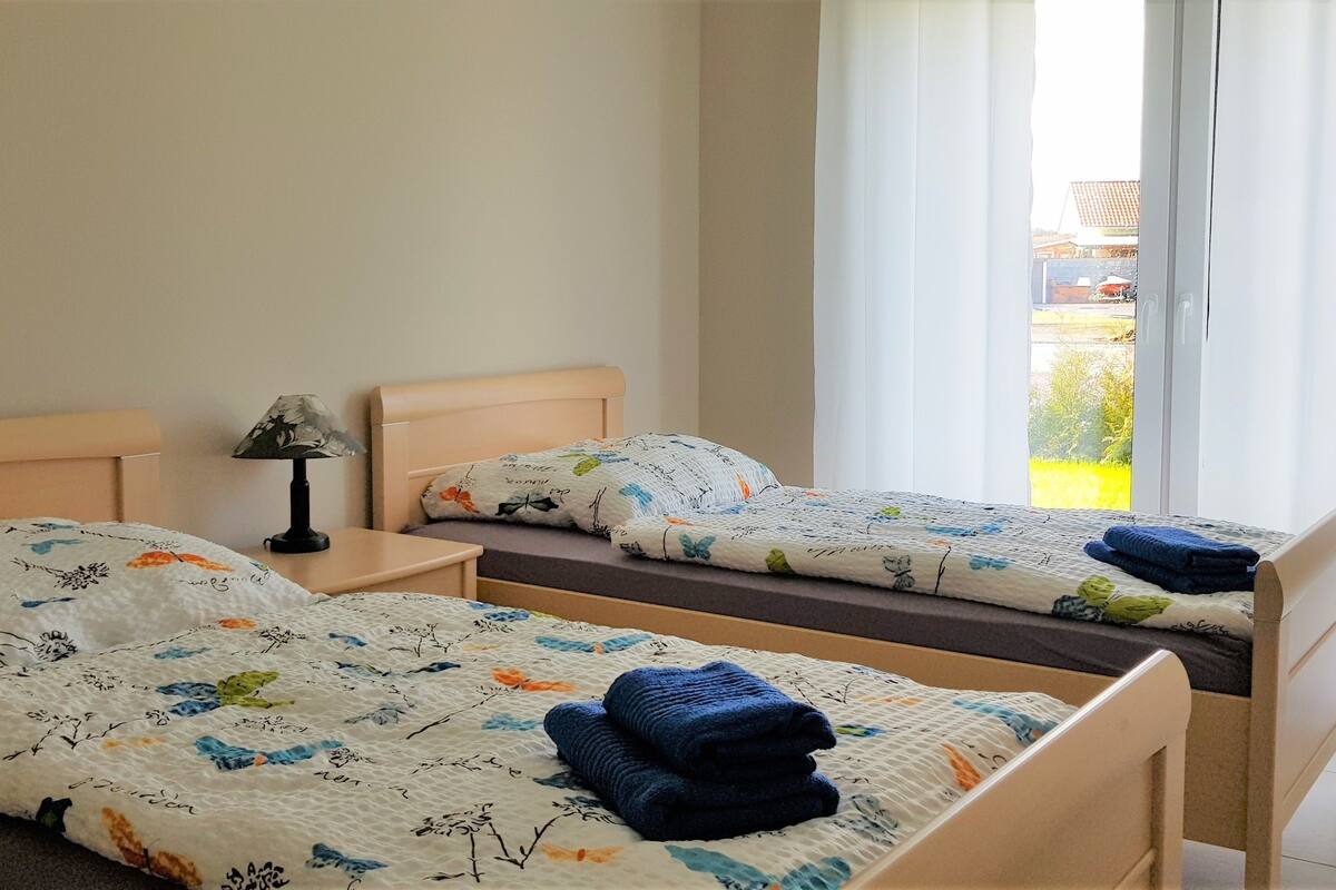 A bedroom with two beds, each with floral bedding and towels.