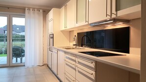 A modern kitchen with a large window, sliding glass door, and a view of the outdoors. - fewosi (Pohlheim)